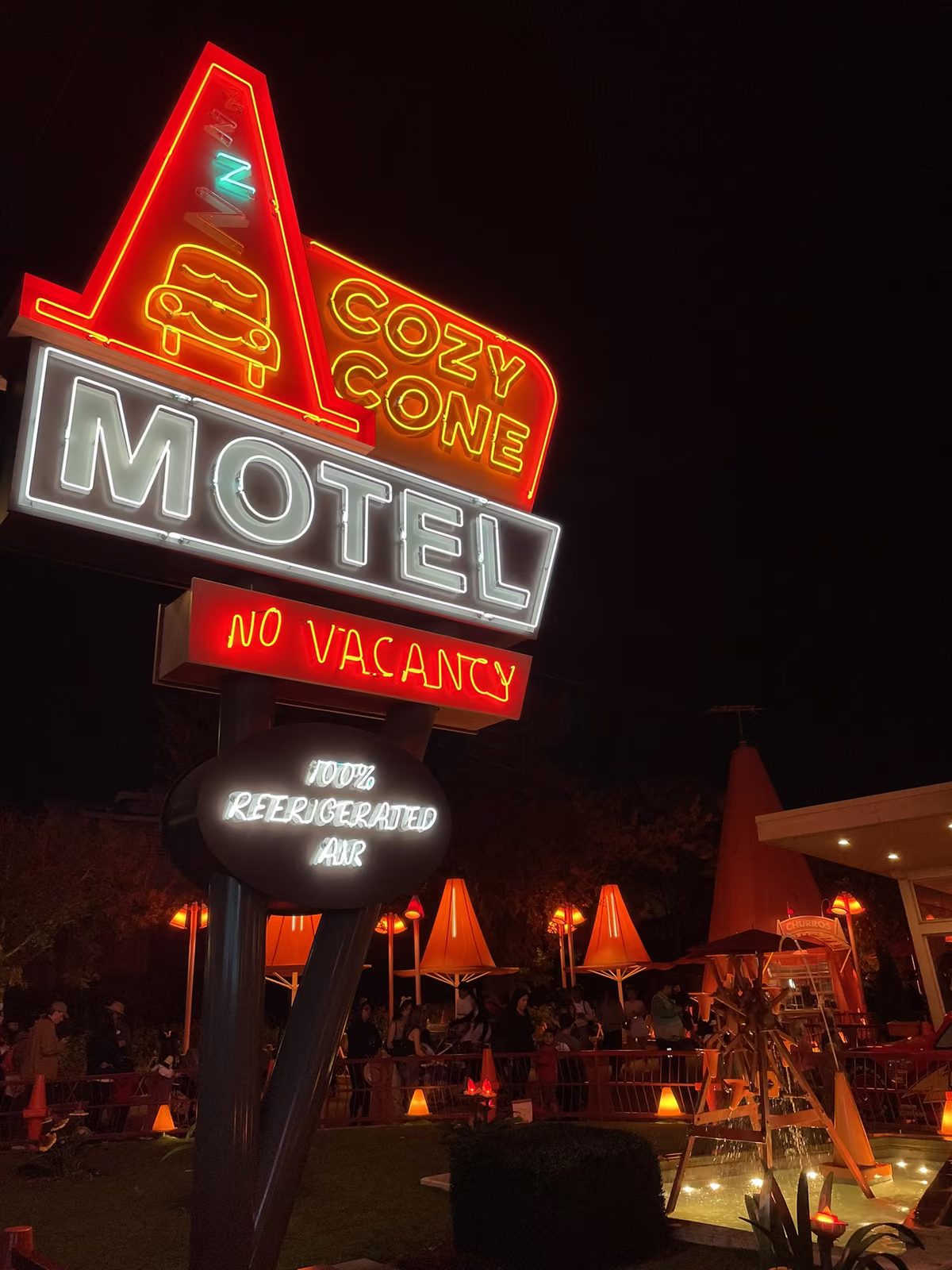 L'enseigne au néon du Cozy Cone Motel illuminée le soir dans Cars Land