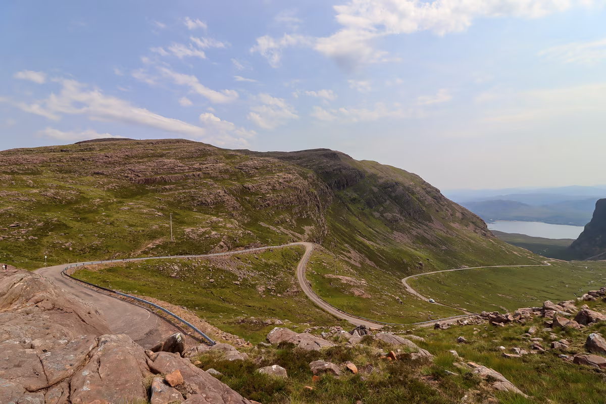 Route sinueuse à flanc de montagne dans les Highlands écossais avec vue sur un loch