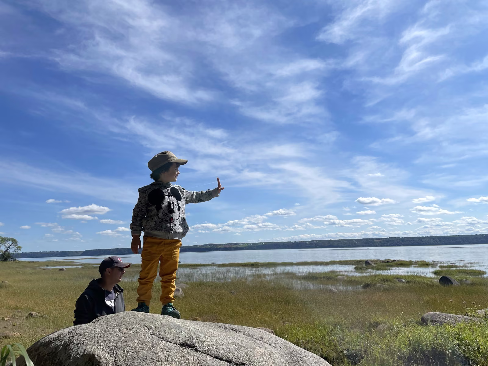 Enfant debout sur un rocher face au fleuve Saint-Laurent sur la grève du Marais Léon-Provancher