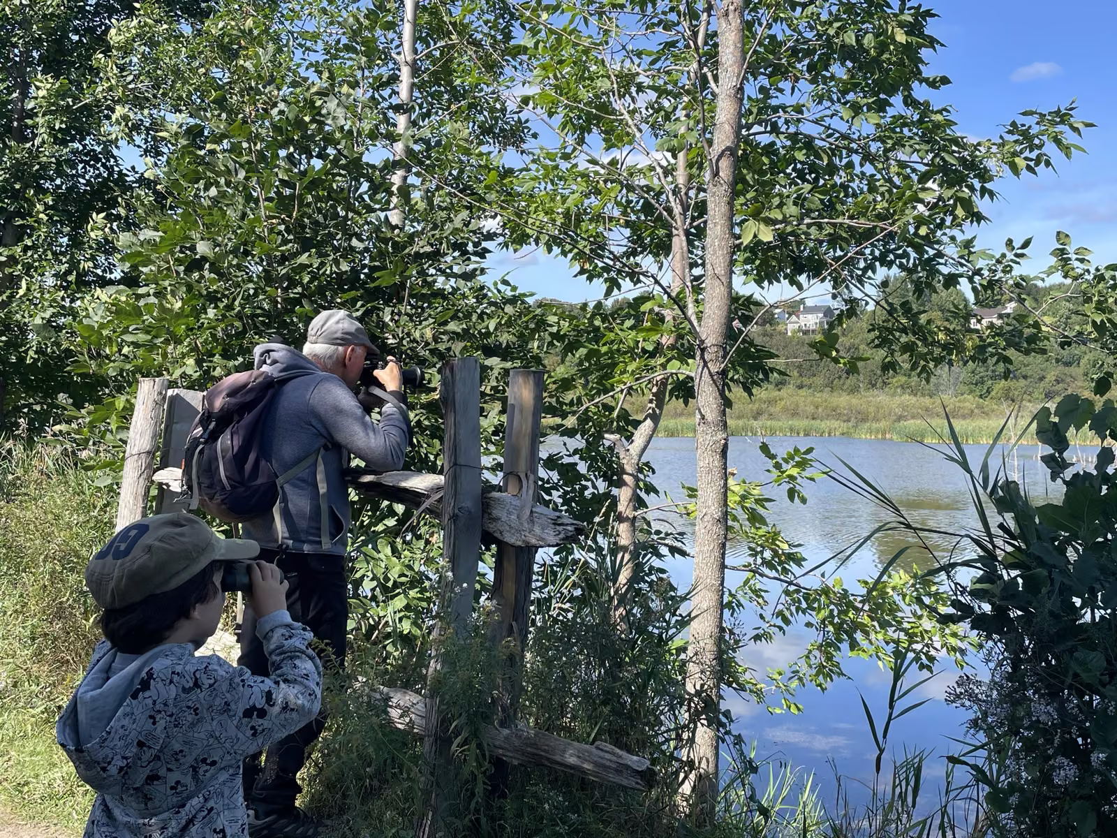 Enfant aux jumelles et adulte photographiant les oiseaux depuis un point d'observation au bord du marais
