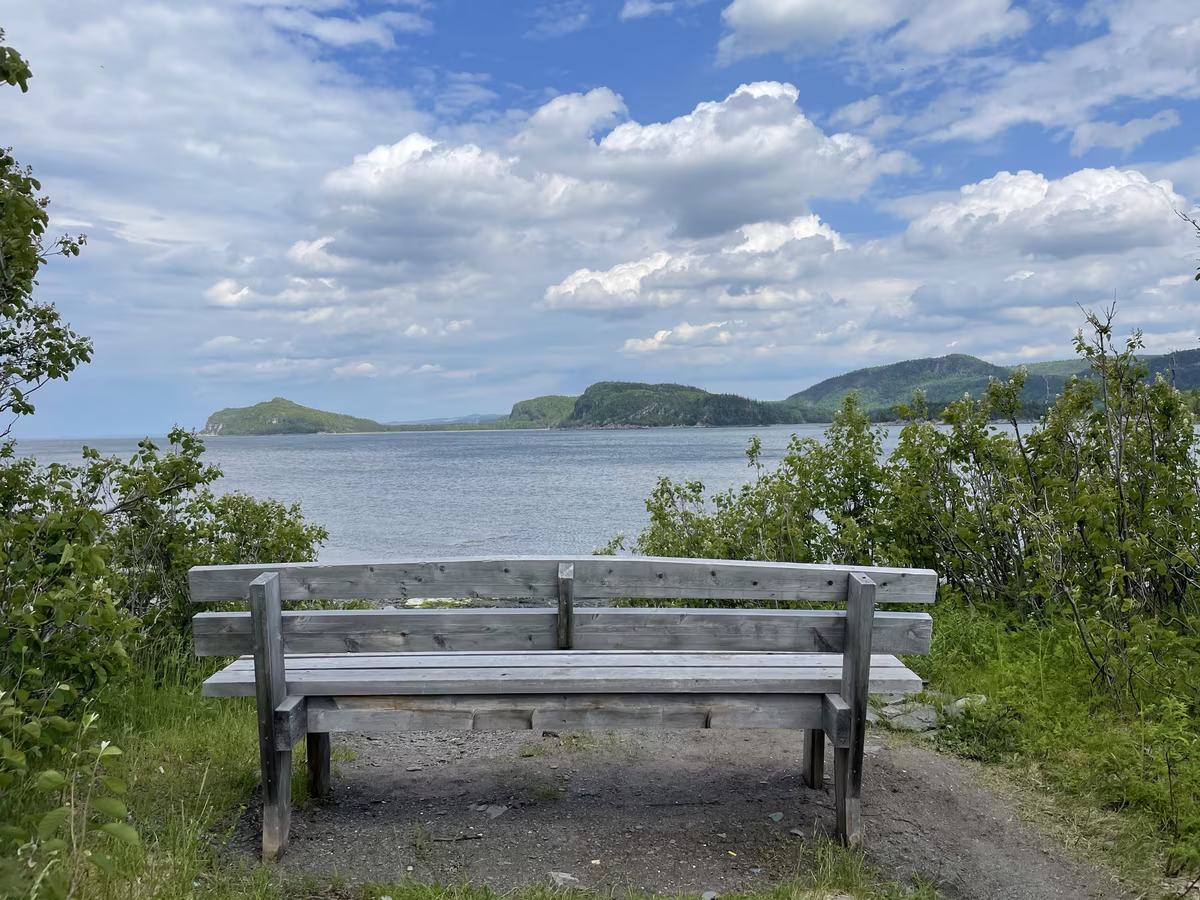 Banc face au fjord du Saguenay en été avec vue sur les montagnes et le fleuve