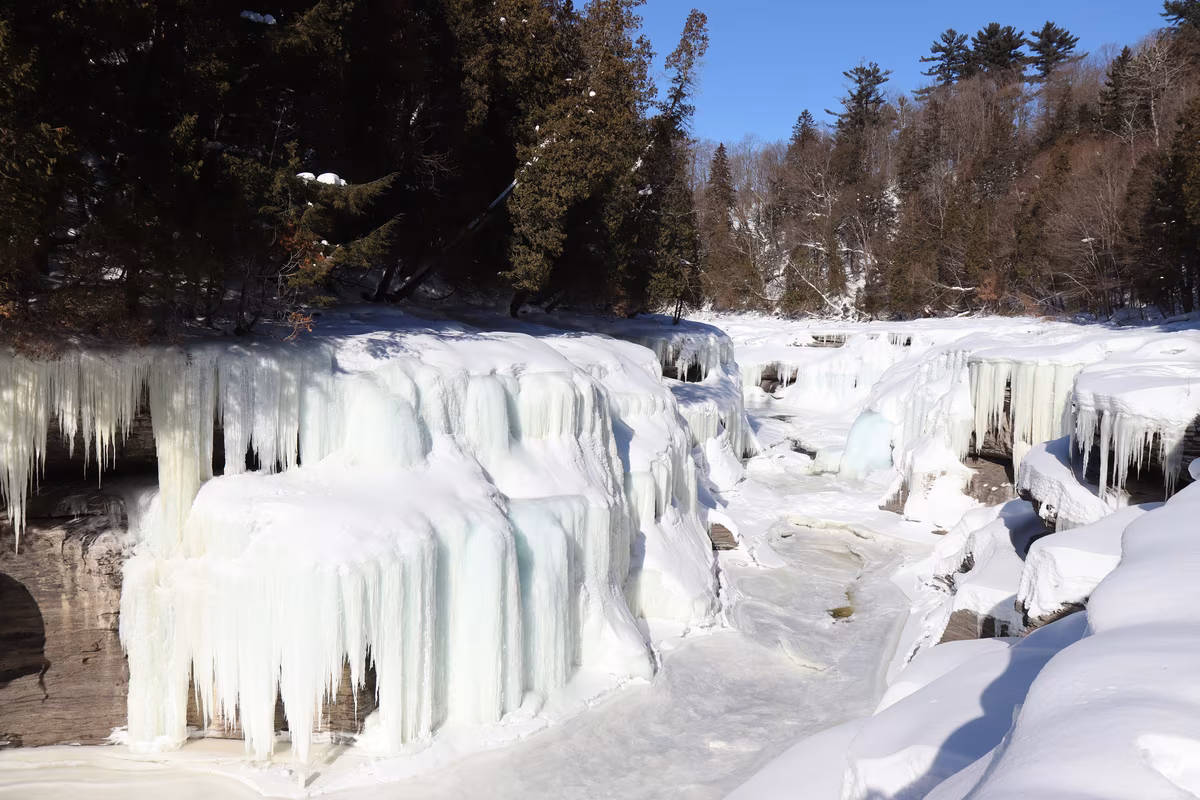Cascade entièrement gelée au Québec en hiver avec stalactites de glace et neige