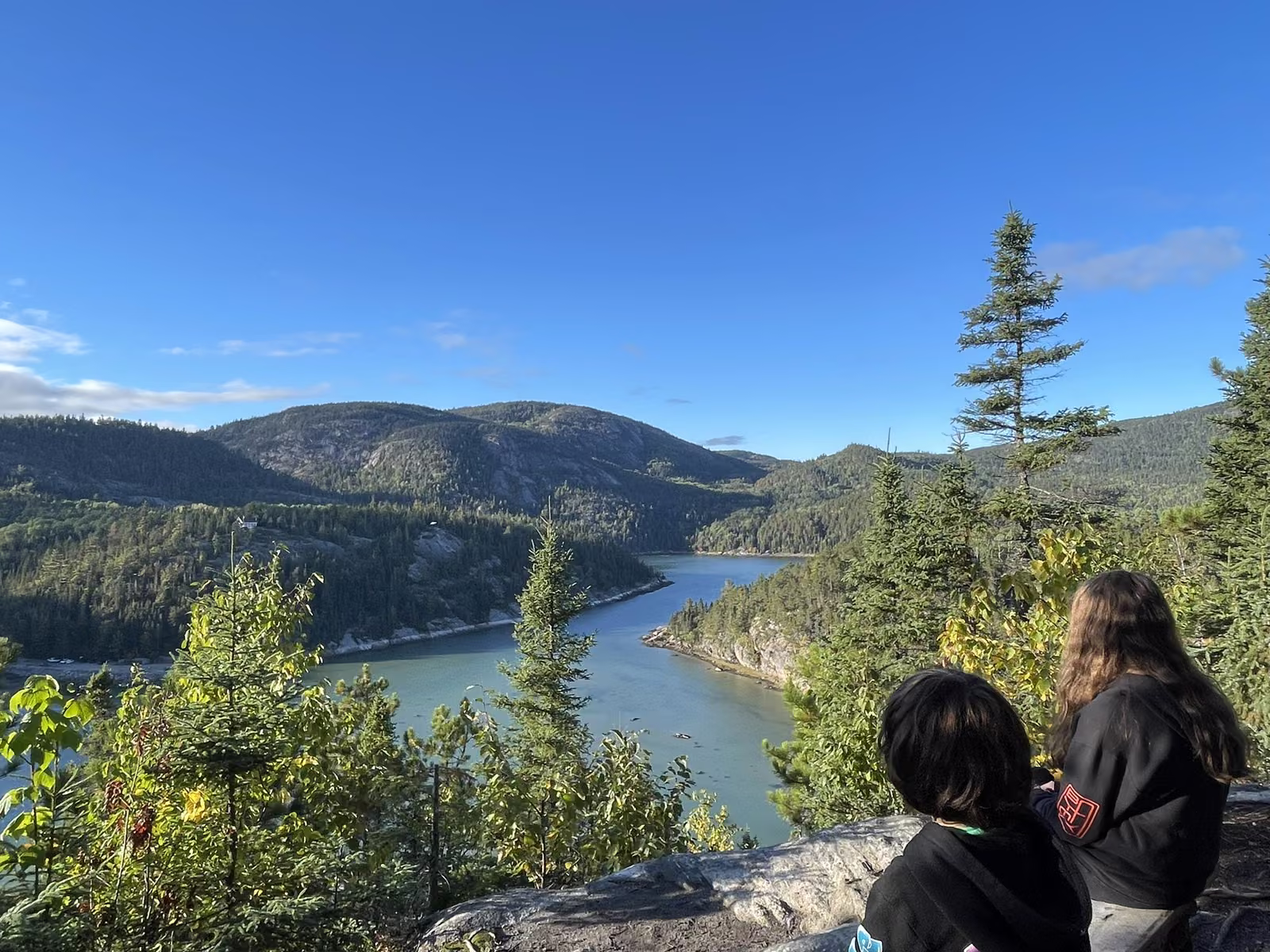 Deux enfants contemplant le fjord du Saguenay depuis un belvédère en forêt