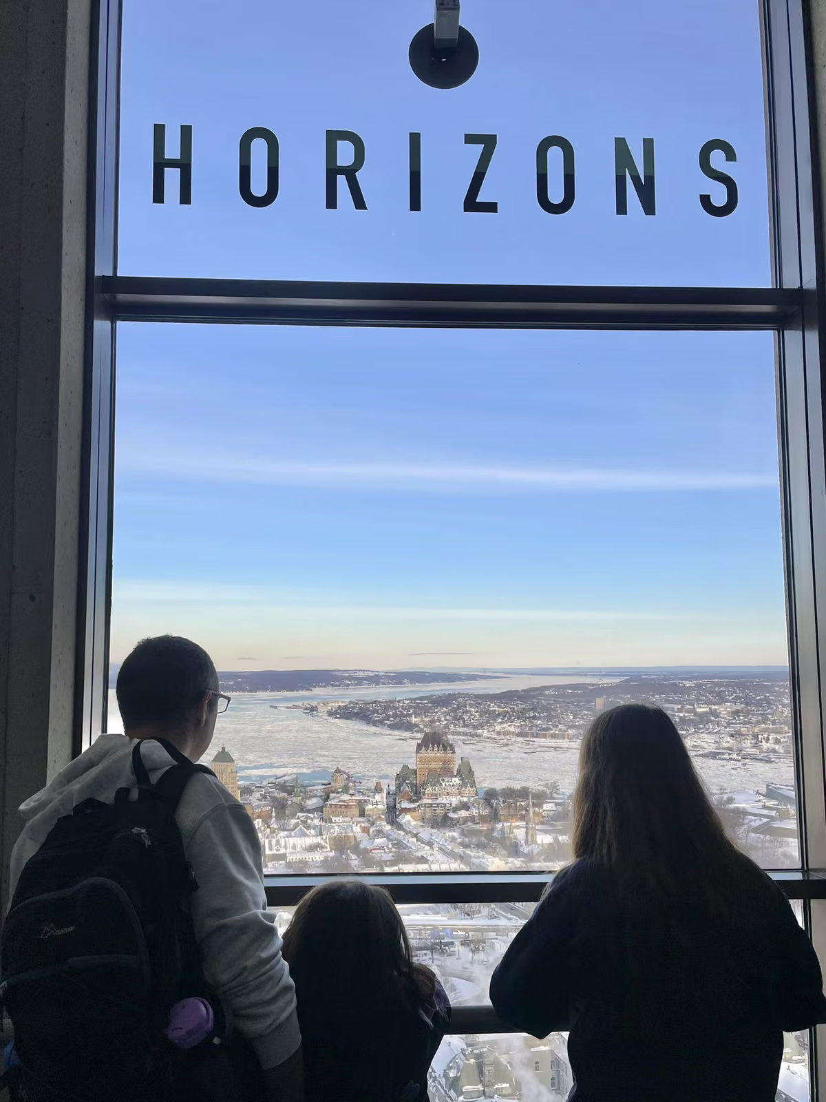 Famille admirant le Château Frontenac et le fleuve gelé depuis l'Observatoire de la Capitale à Québec